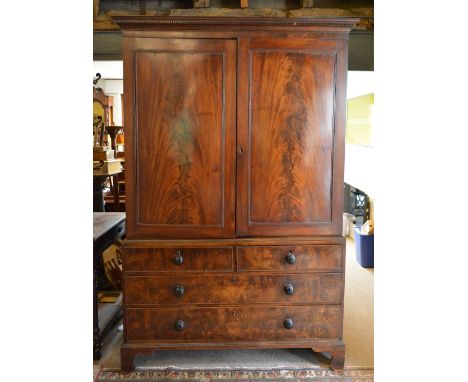 An Early 19th Century Mahogany Linen Press, the moulded cornice above two panelled doors enclosing sliding trays, the lower s