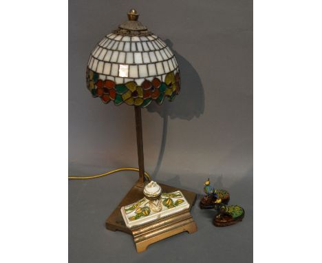 A Tiffany Style Brass Table Lamp with incorporated Inkwell, together with two enamel models in the form of peacocks with hard