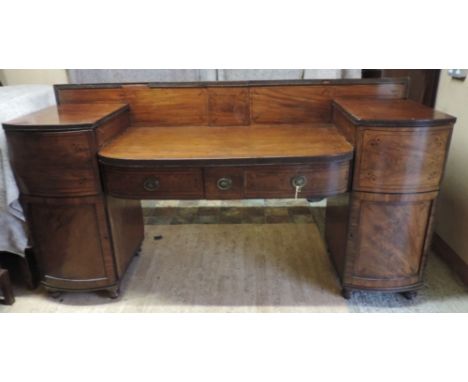 A Regency Mahogany Pedestal Sideboard, the shaped back above two frieze drawers flanked by bow fronted cupboards, raised upon