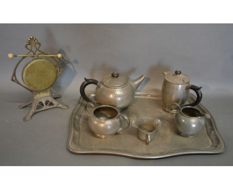 A Tudric Beaten Pewter Tea Service comprising teapot, hot water pot, cream jug and sugar bowl upon a shaped tray, together wi