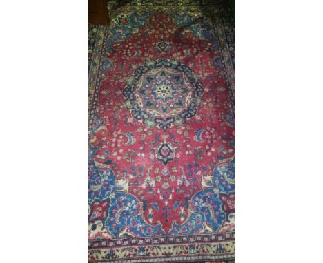 An Old Red Ground Persian Mashad Carpet with traditional medallion design. 144'' X 66''.