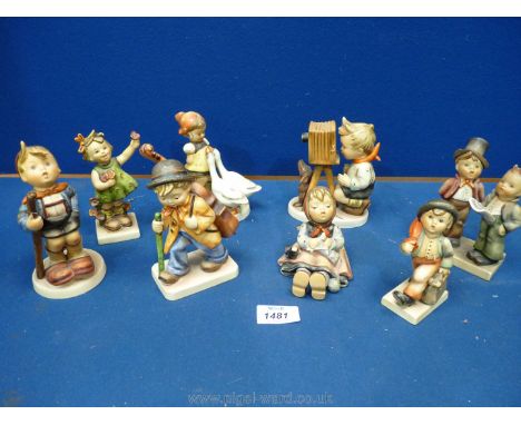 Six Hummel figures including a boy with a cello, carol singers, and a boy with a camera, boy with umbrella, girl with ducks, 