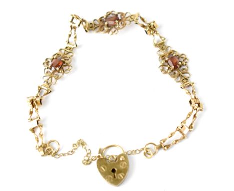 A 19th century 9ct gold bracelet with three red stones within openwork flower heads joined with bow links, united with heart 