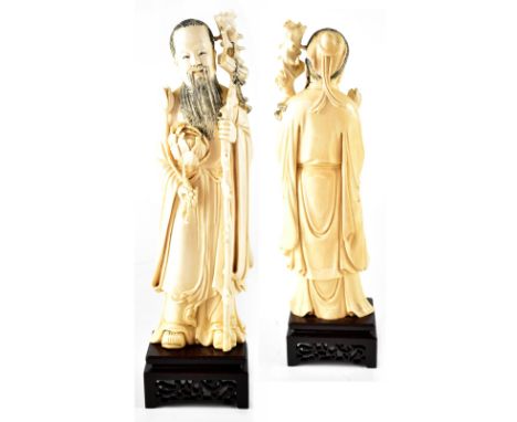 An early 20th century Chinese ivory figure of a religious travelling gentleman, carrying a staff, scroll and large lotus flow