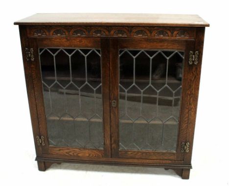 An early 20th century glazed bookcase with carved decoration to the frieze, above pair of astragal glazed doors, raised on st