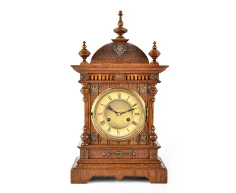 A late 19th/early 20th century German oak-cased mantel clock, the ivorine dial set with Roman numerals, the case enclosing a 