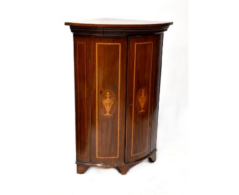 A 19th century mahogany inlaid bow-front wall-hanging corner cupboard with urn and swag inlay to the twin doors, to block sup