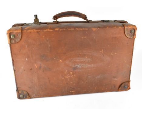 A vintage brown leather suitcase with a Cunard White Star Line label with image of a sailing ship and partial destination lab