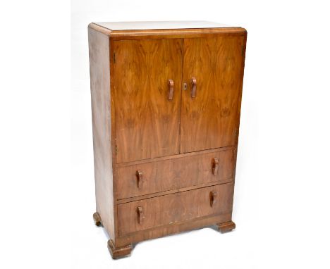 A 1930s walnut veneered tallboy with pair of cupboard doors above two long drawers, on ogee bracket feet, height 127cm, width