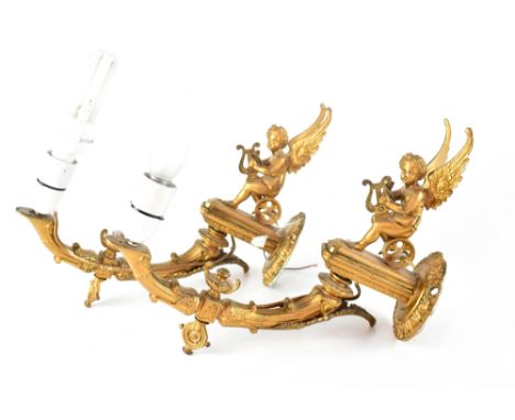 A pair of Louis XXIV inspired brass gilt wall lights, seated cherub on winged chariot playing a lyre to curving arm light fit