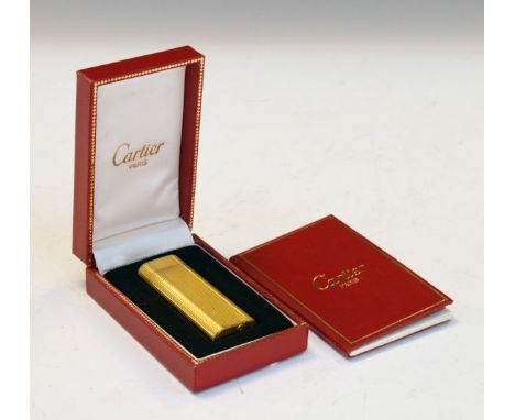 Cartier gold plated cigarette lighter having allover engine turned decoration, cased   Condition: 