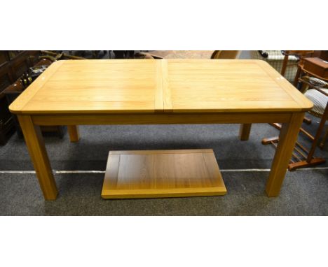 A contemporary light oak draw leaf dining table