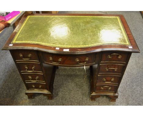 An elegant reproduction mahogany serpentine fronted knee hole desk, tooled leather inlay, central cock beaded drawer flanked 