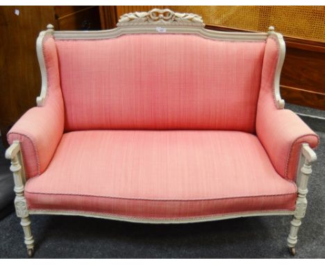 A Louis XIV style two seater sofa,  carved central pierced ribbon  tied foliage, shaped cresting rail,  pink upholstery, scro