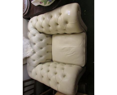 A BUTTON BACK TUB ARMCHAIR IN CREAM SIMULATED LEATHER.