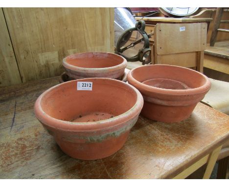 Three shallow circular terracotta pots and three terracotta saucers 