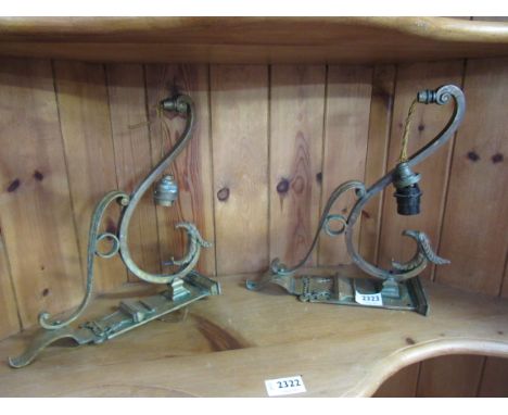 A pair of ornate brass griffin head wall light brackets 