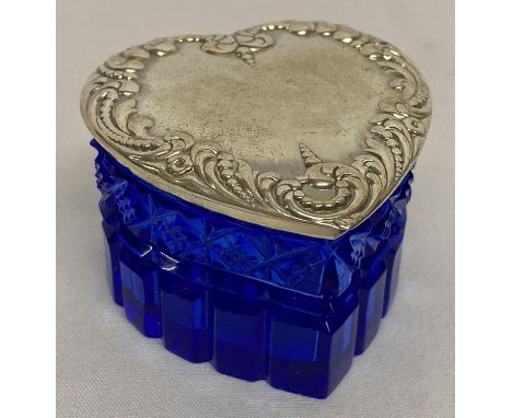 A heart shaped blue cut glass trinket box with embossed decoration to lid.  Lid marked sterling.  Approx. 4.5cm tall.