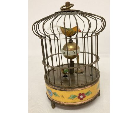 An ornamental wind up birdcage clock with yellow cloisonné panel to base.  The cage features two small feathered birds. Windi