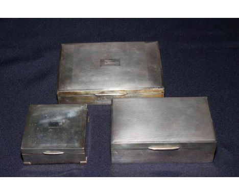 Three silver engine-turned cigarette boxes, the largest one with inscription, 16.5cm across.