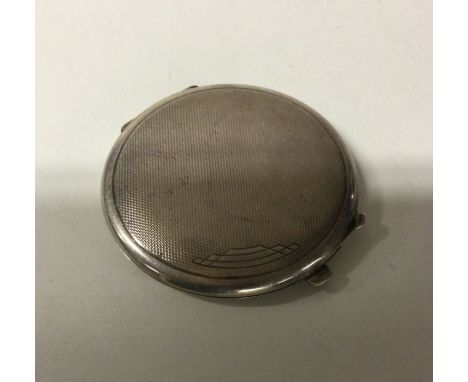 An engine turned silver compact with hinged top. Approx. 82 grams. Est. £30 - £50.