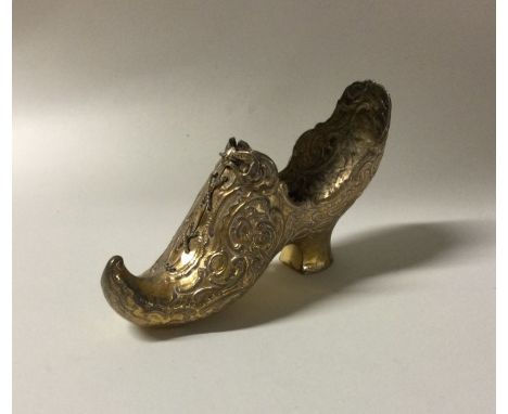 A heavy silver gilt model of a shoe with chased decoration. Approx. 60 grams. Est. £30 - £50.