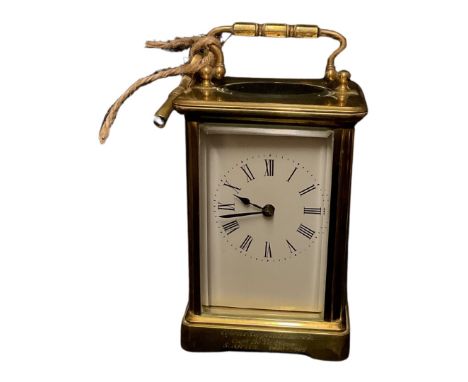 An early 20th century brass carriage clock, the white enamel dial with Roman numerals, swing handle, 11cm high