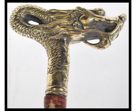 A bamboo walking stick having a brass handle in the form of a Chinese dragon. Measures 29cm high.