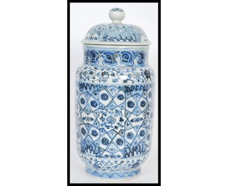 A Chinese hand painted blue and white ceramic vase and cover of cylindrical form having a bell shaped finial lid. Six charact