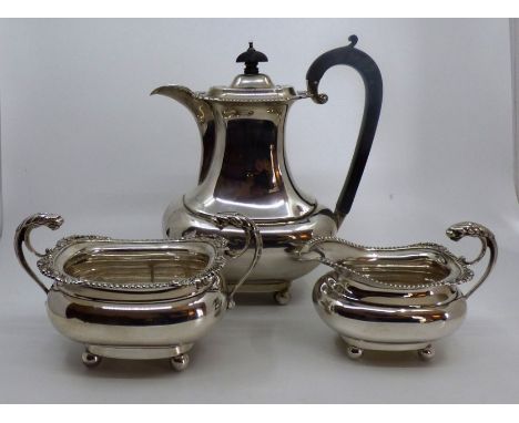 An Edwardian silver three piece coffee service of rounded baluster form on ball feet, comprising coffee pot with ebonized han