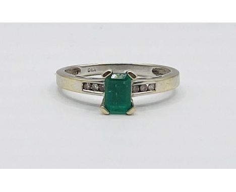 White metal ring, tests as 18ct gold. Emerald cut emerald, set with six melee diamonds. (Size M ½)