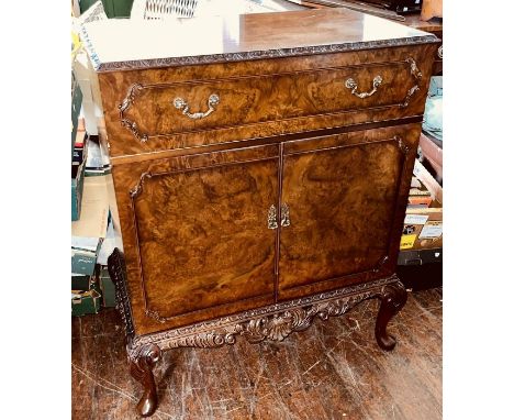 A 20th century walnut television cabinet, caddy top carved edge, above a frieze drawer over a two panel cupboard, on a carved