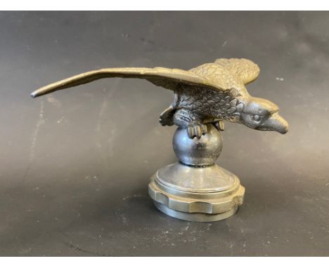 A Desmo car accessory mascot in the form of a bird of prey crouched on a sphere, mounted on a radiator cap. 