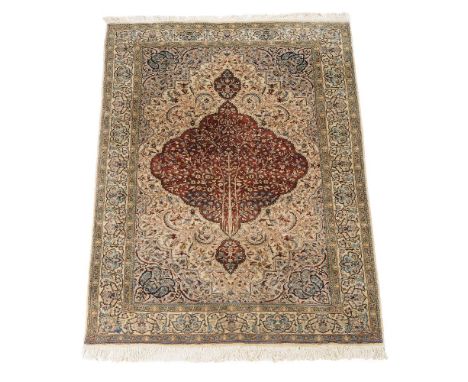 A woven carpet in Kashan style, the pale field decorated profusely with polychrome floral and foliate motifs, approximately 2