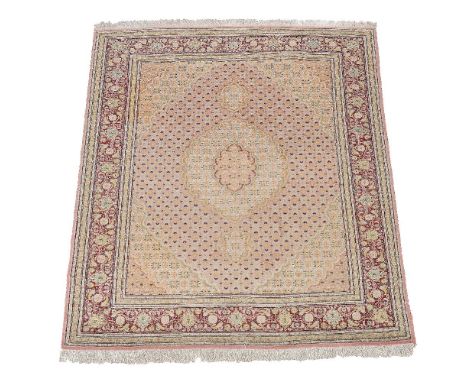 A Tabriz rug,  the pale pink field decorated by a medallion and cornered by spandrels, within a claret border, approximately 