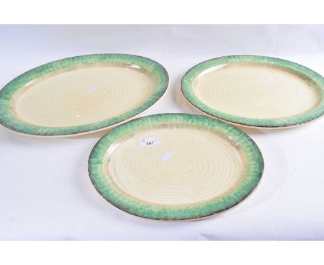 A graduated set of three Clarice Cliff bizarre serving dishes of ribbed form with green mottled borders, largest 41cm