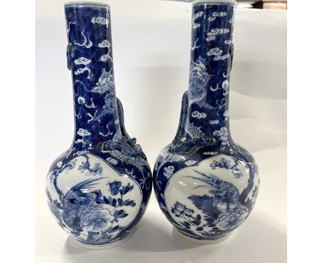 A pair of Chinese bottle vases 19th century decorated in Kangxi style the blue ground with dragons and panels of brids amongs