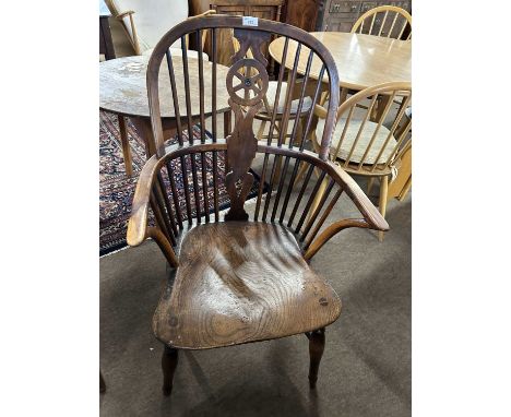 A 19th Century yew and elm Windsor chair with central wheel formed splat and stick back raised on turned legs with crinoline 