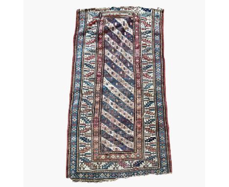 A Caucasian long rug, late 19th century, the indigo and ivory barbers pole field with hooked guls, with an ivory serrated lea