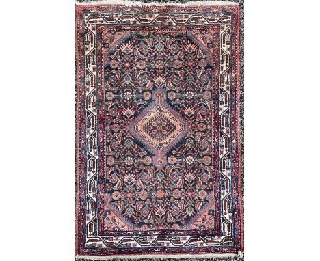 A Hamadan rug, North West Persia, circa 1920, the dark indigo herati field with a central serrated lozenge medallion, within 