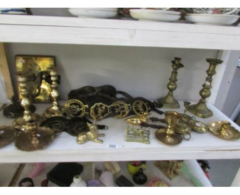 A shelf of brass ware including horse brasses, candlesticks etc