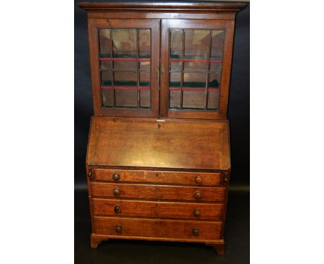 A George III oak bureau bookcase, stepped cornice over two glazed doors enclosing shelving to top, fall front enclosing fitte