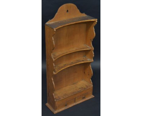 A 19th century pine concave fronted spoon rack, shaped cresting above two rows of apertures, a shelf and a niche, the base wi