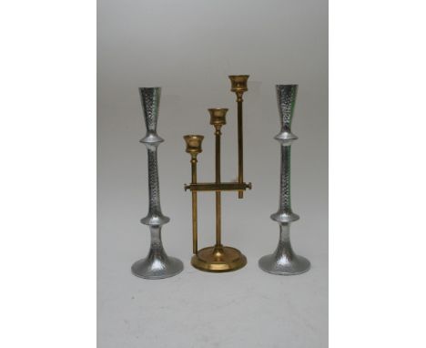 An adjustable triple sconce brass candlestick having narrow rod supports and shaped flared sconces and a pair of silver colou