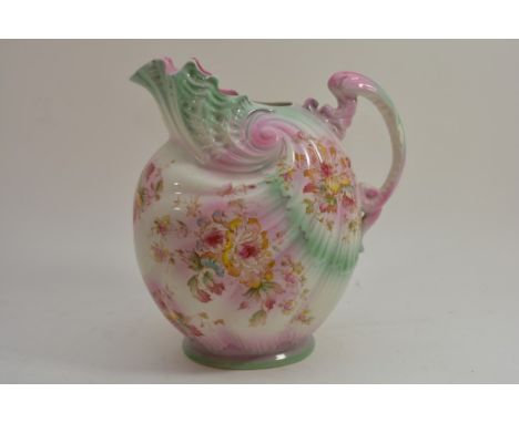 A large ceramic jug with hand painted floral decoration on a pink and green ground.