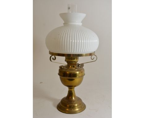 A brass oil lamp with white glass shade.