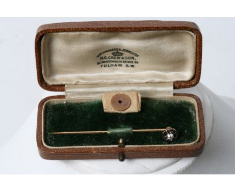 A gold stick pin set with a single diamond, cased