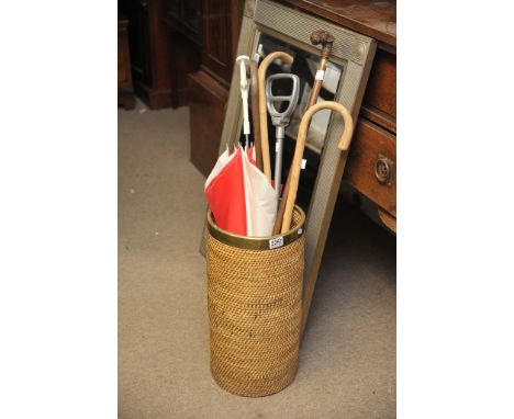 A woven stick stand with four walking sticks, shooting stick and umbrella.