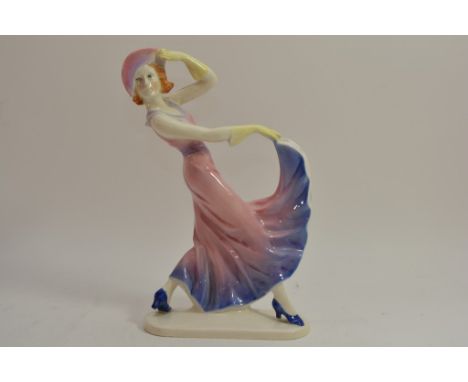 An Art Deco ceramic figure of a lady in a pink and blue dress.