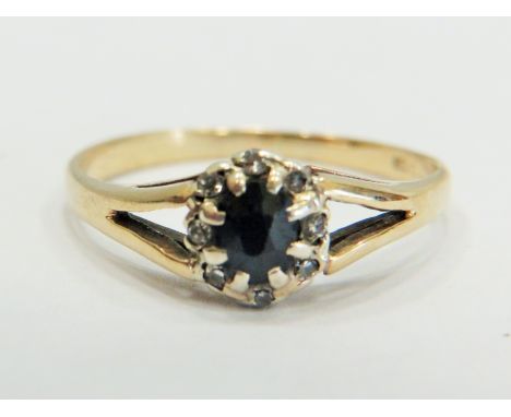 9ct Yellow Gold ring set with a central Sapphire with large claw mounts and surrounded by small Melee Diamonds.  Finger size 